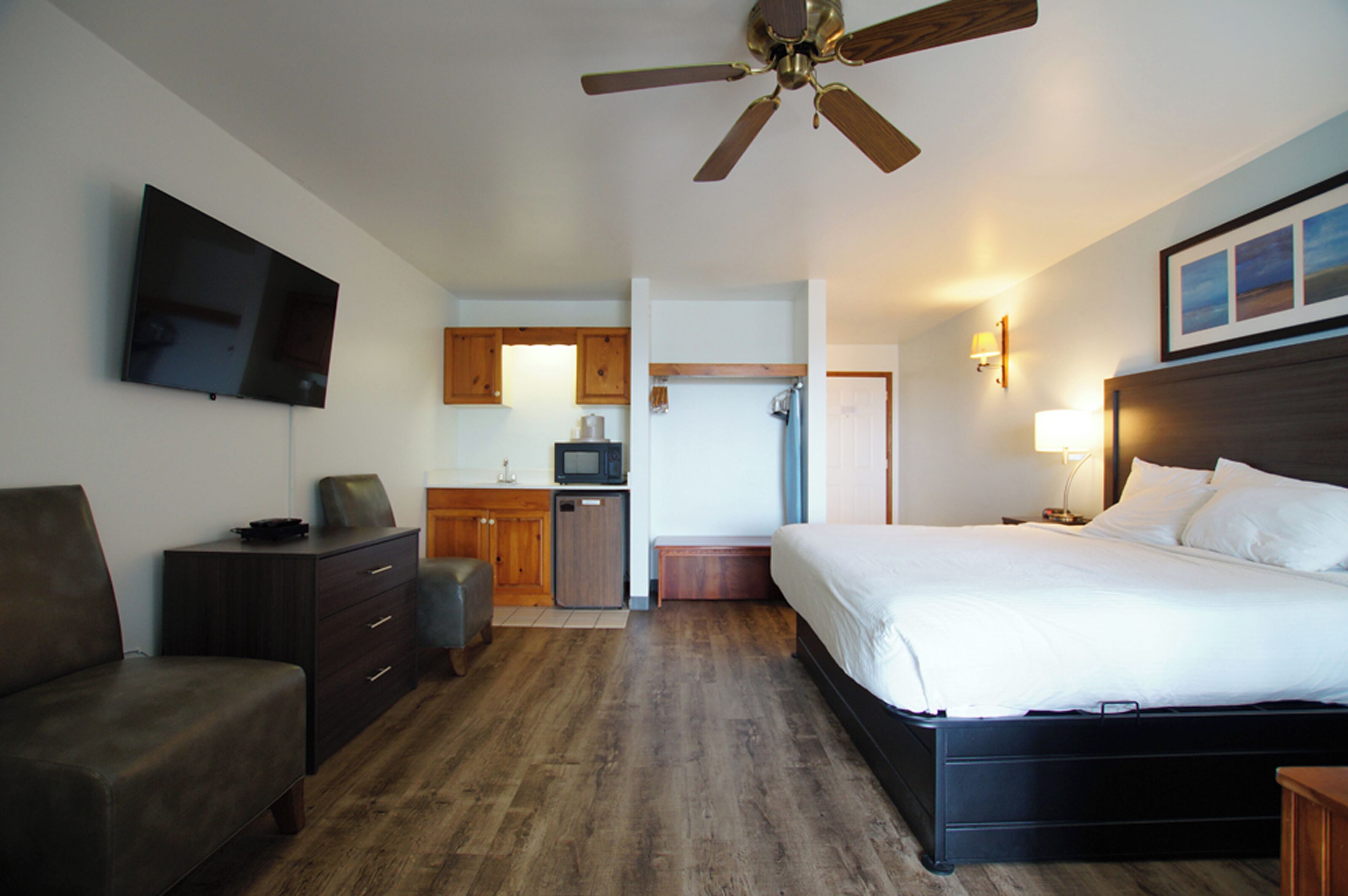 A hotel room with a bed, a desk, a television, and a ceiling fan.