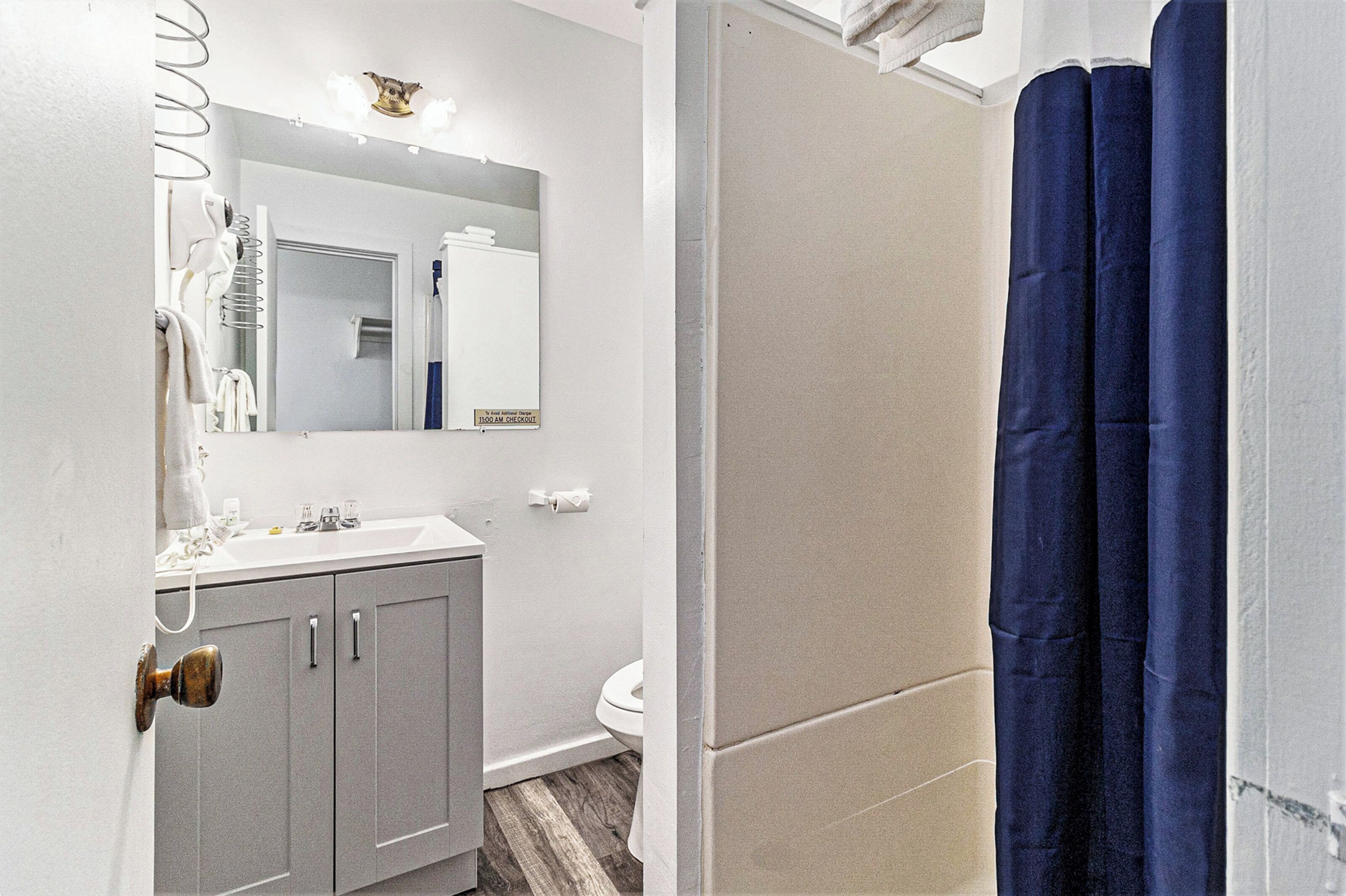 A bathroom with a white sink, mirror, and toilet.