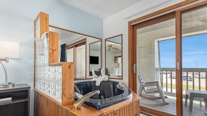 A bathroom with a wooden vanity, a large mirror, a bathtub, and a sliding glass door leading to a balcony.