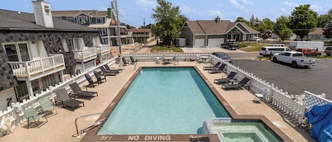 A rectangular swimming pool with a 'NO DIVING' sign, surrounded by lounge chairs and a white fence.