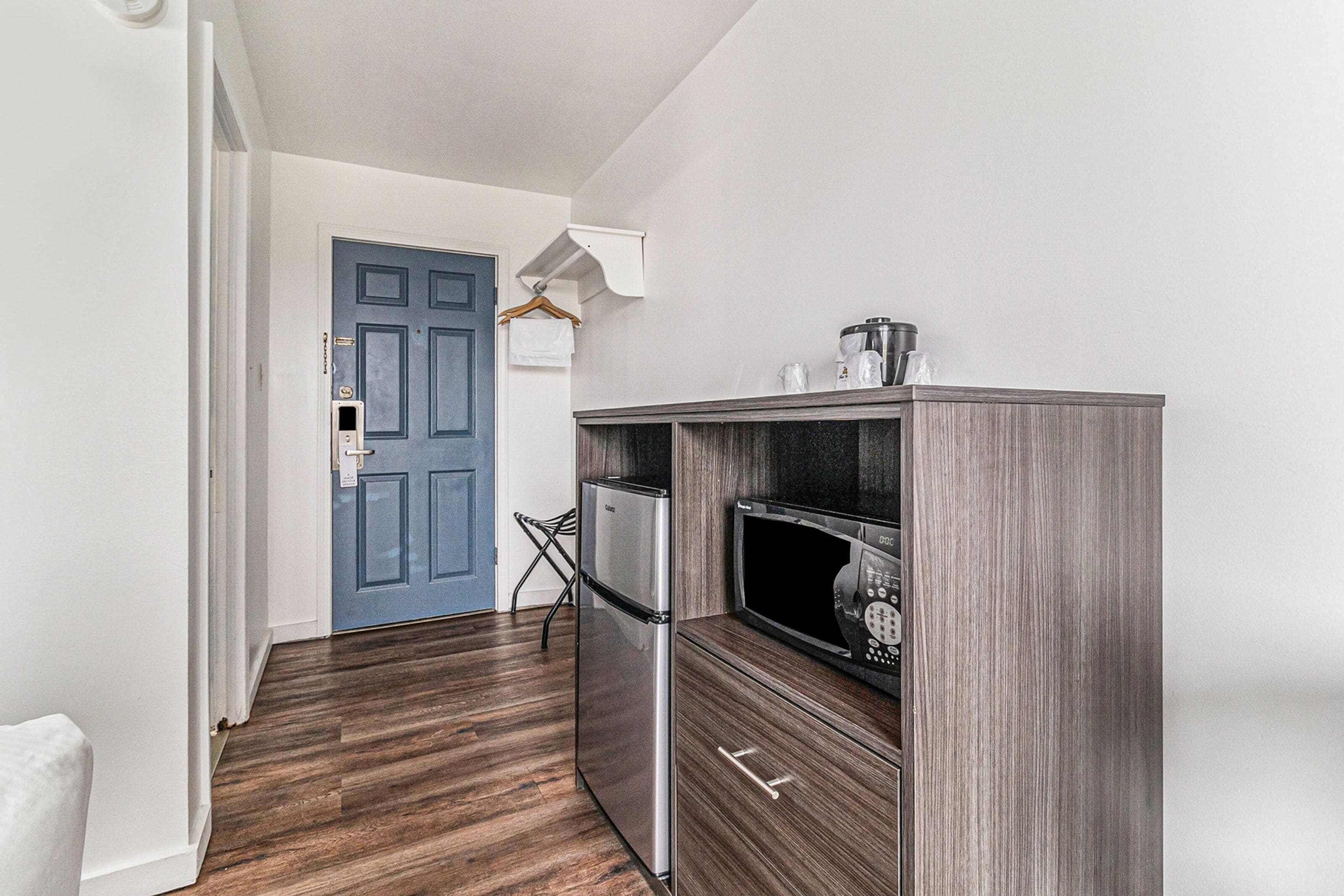 A kitchen with a refrigerator, microwave, and a coffee maker on a wooden cabinet.