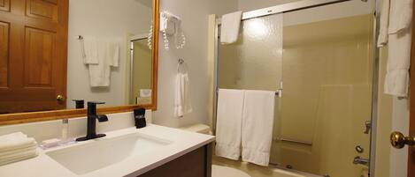 A bathroom with a sink, toilet, and a glass-enclosed shower.