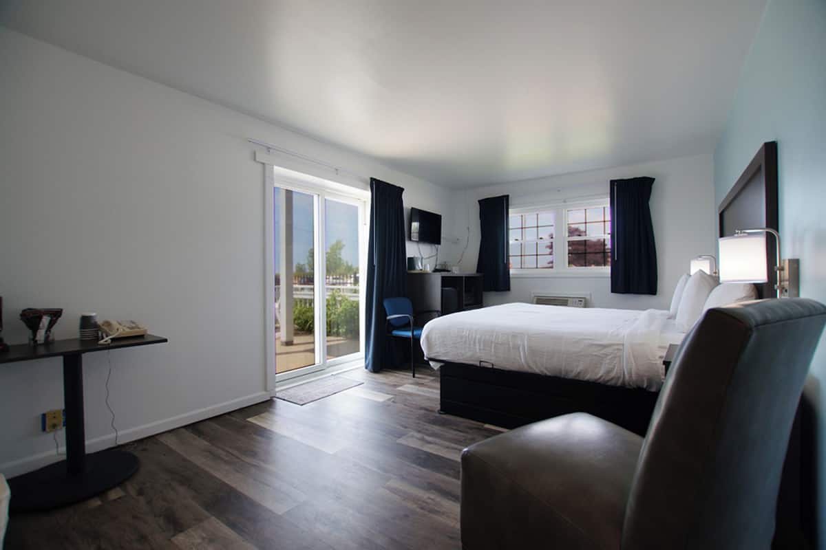 Quarto de hotel com uma cama, uma escrivaninha, uma cadeira e uma televisão.