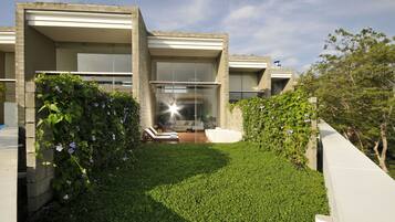 Une maison moderne dotée d’un jardin bien entretenu, d’un espace extérieur aménagé avec des sièges et d’une grande fenêtre.