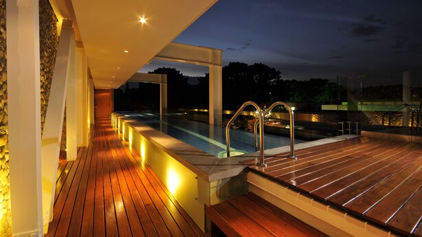 Eine Holzterrasse mit Pool und einer Steinmauer.