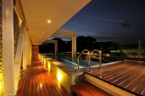 A wooden deck with a pool and a stone wall. - AcquaSanta Lofts Hotel (Cali)