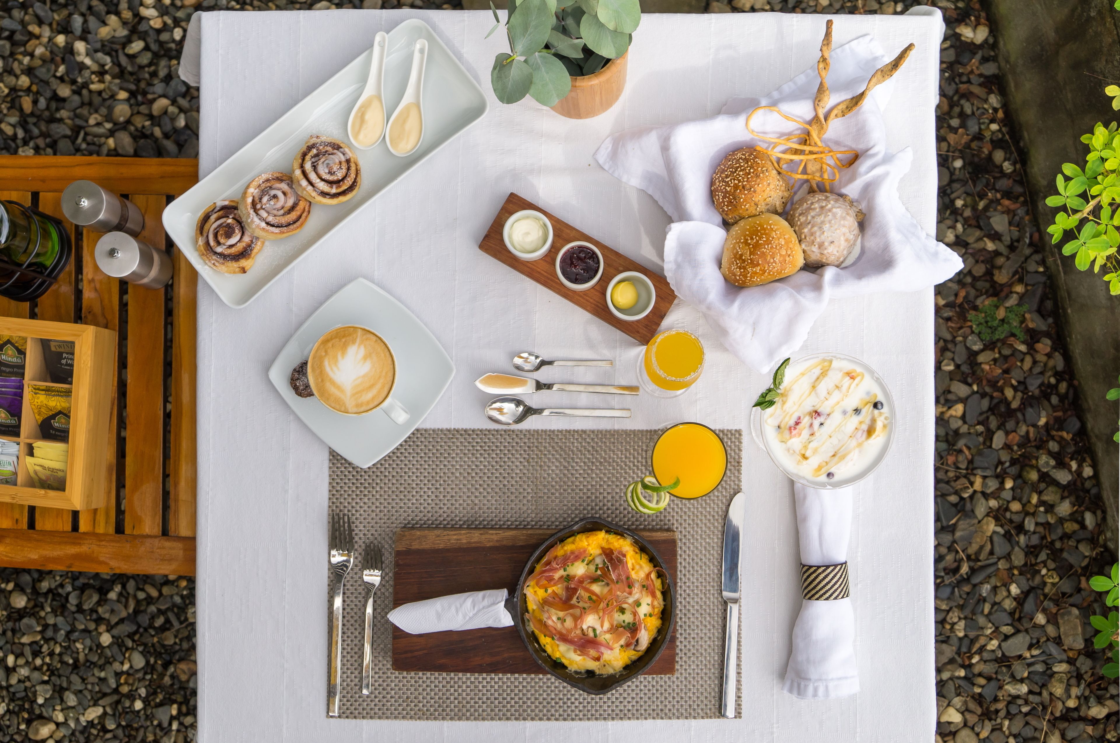 A breakfast setting with a variety of food items, including pastries, a coffee drink, and a dish with meat and vegetables.