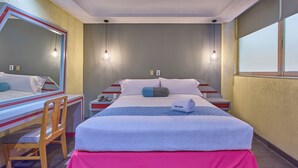 A hotel room with a bed, a desk, a chair, a mirror, and a window. - Frida Costa Azul (Mexico City)
