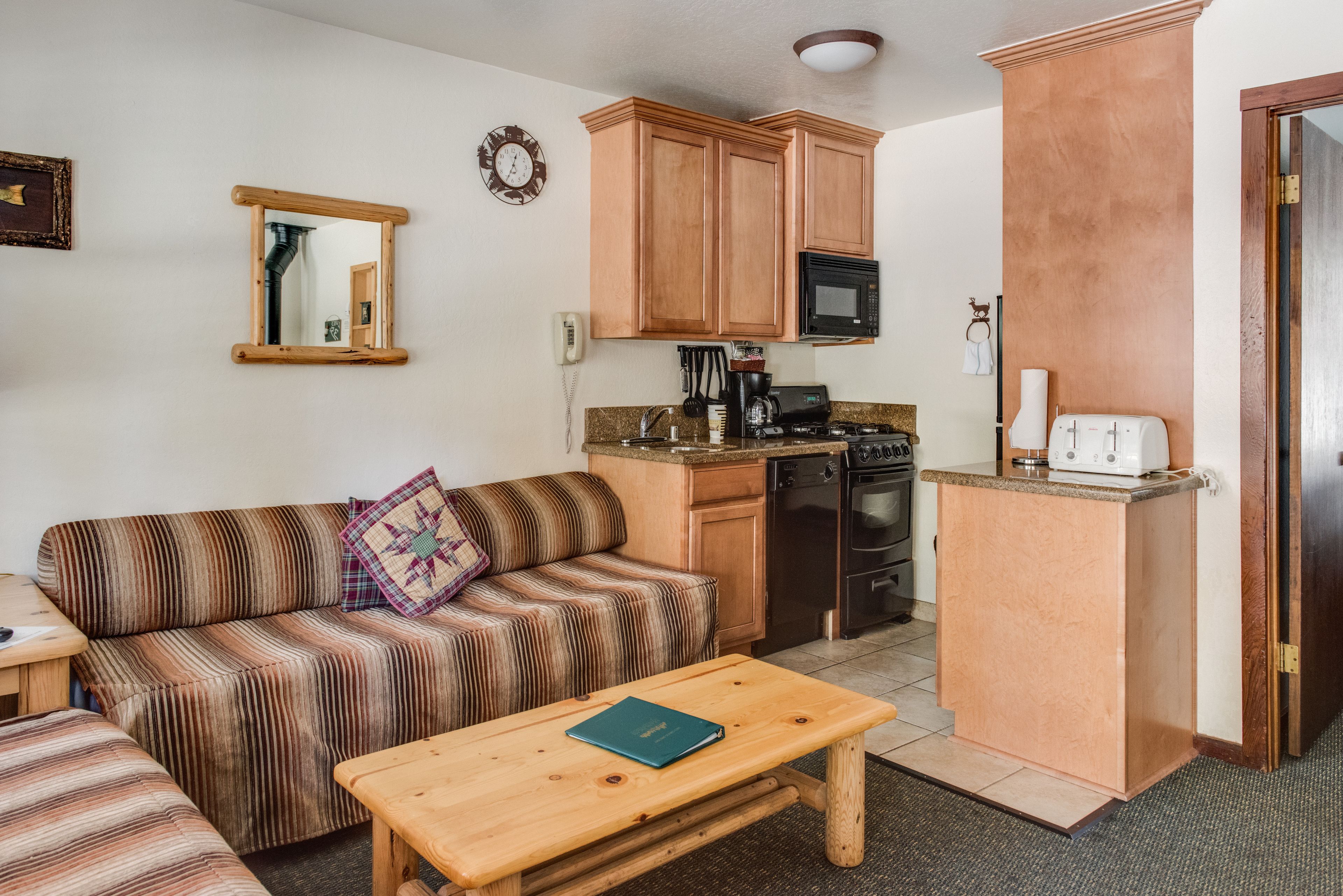 Un espacio habitable compacto con un sofá, una mesa de centro, una zona de cocina que incluye un microondas, cocina y una pequeña encimera.