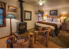 Un dormitorio acogedor con cama, una silla de madera, una lámpara, un mapa y una chimenea.