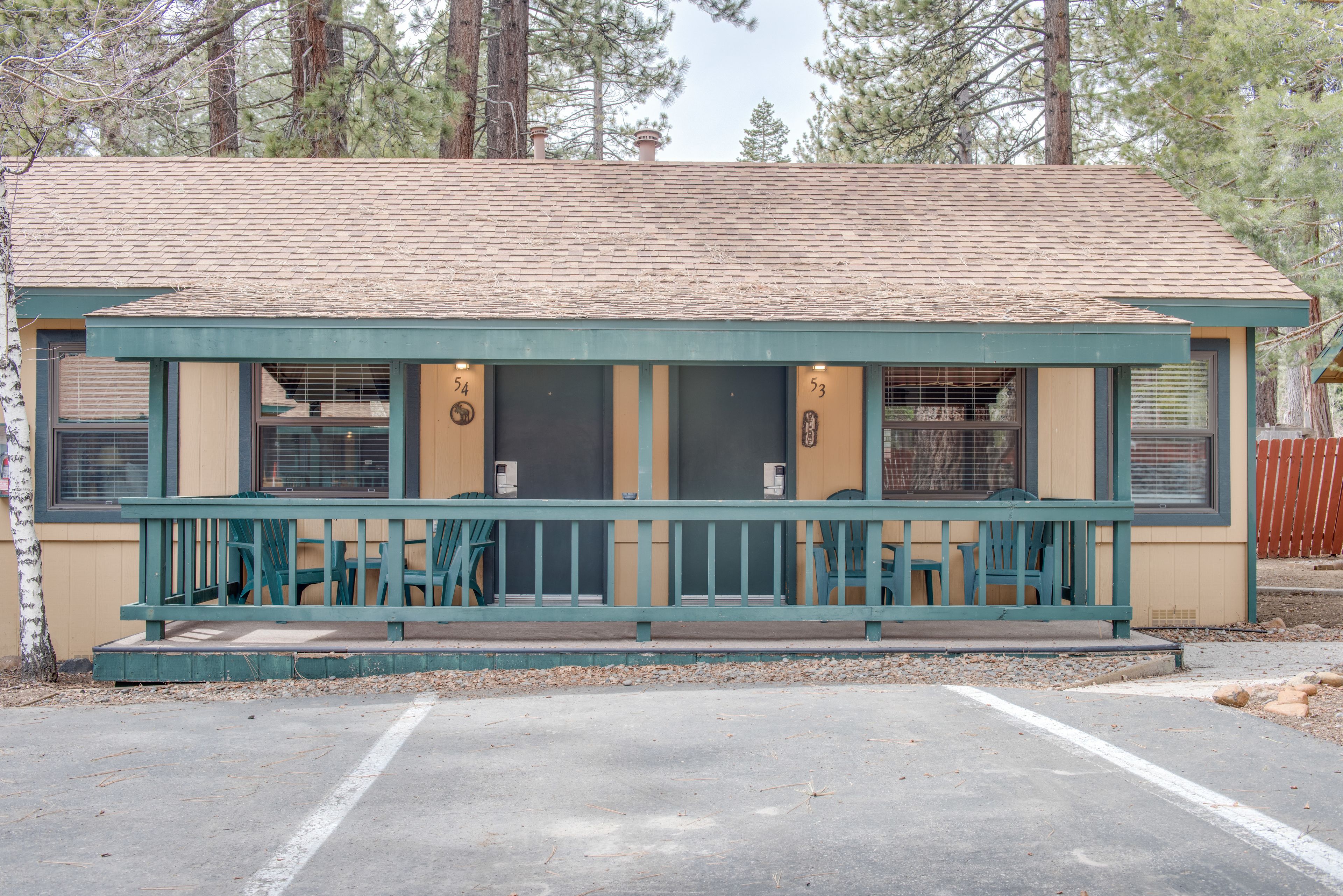 A small, single-story building with a porch, numbered rooms, and a parking area.