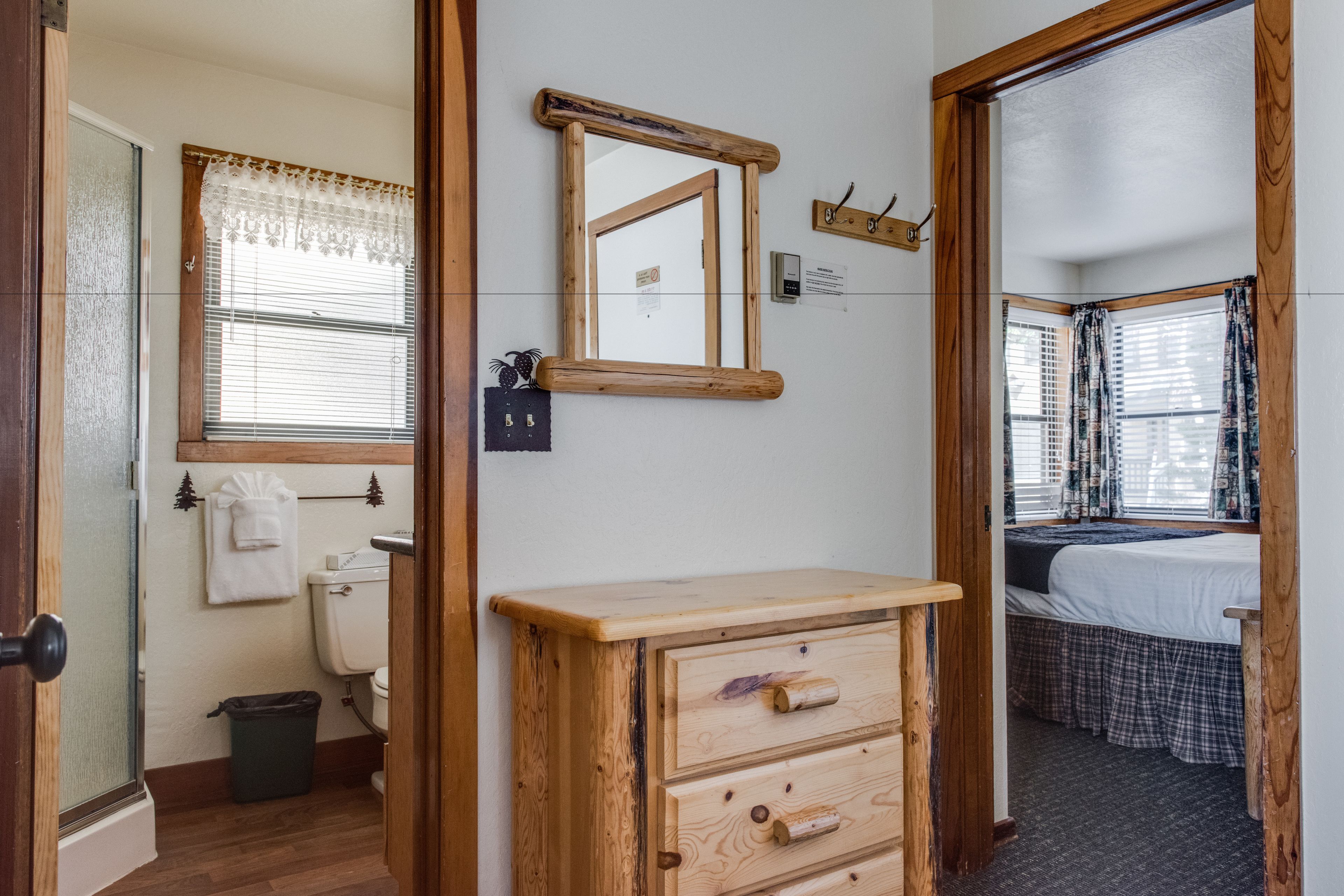 A bathroom with a toilet, a sink, and a mirror. There is a window with blinds and a towel hanging on the wall.