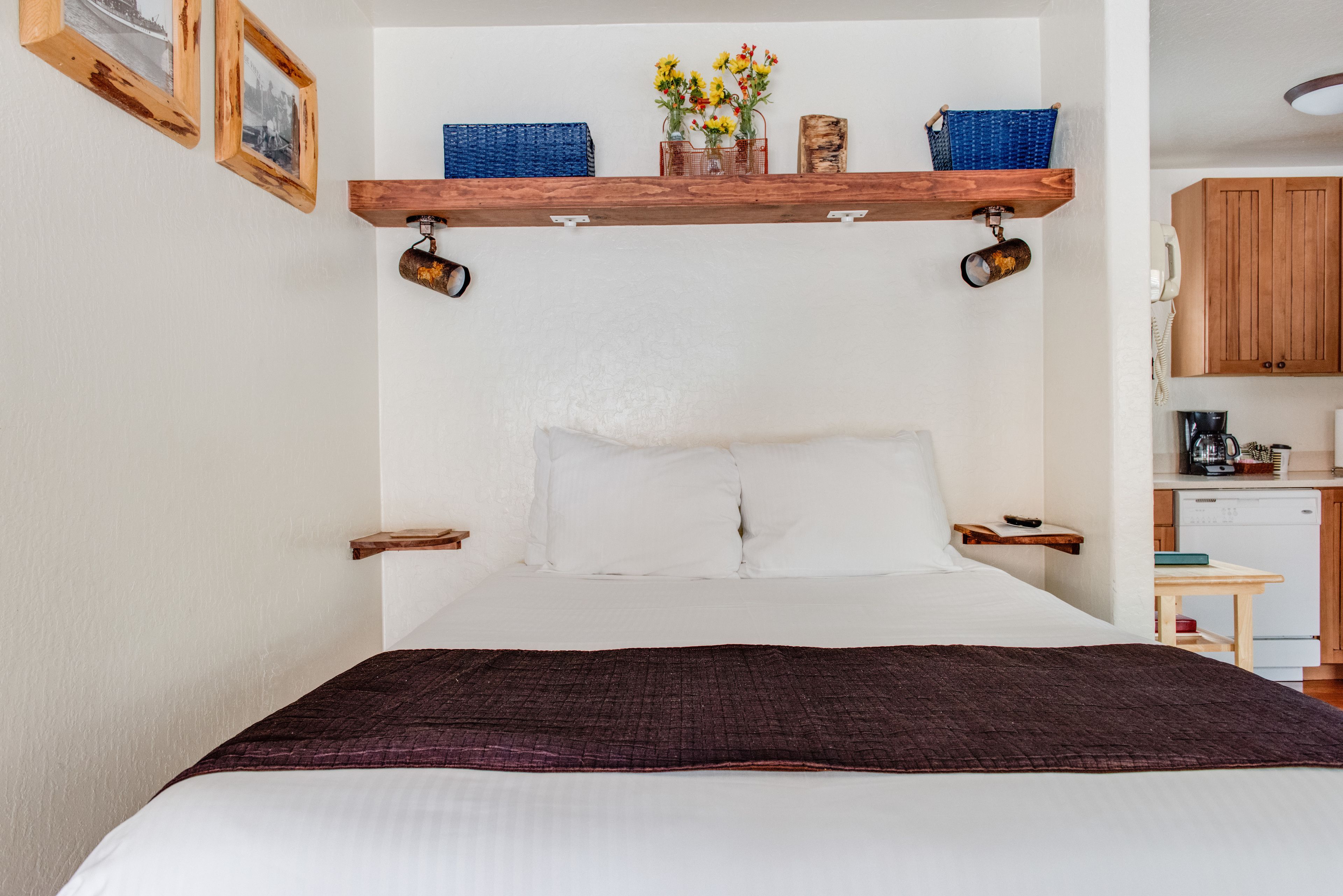 Un dormitorio con una cama grande, cabecera de madera y un estante sobre la cama con objetos decorativos.