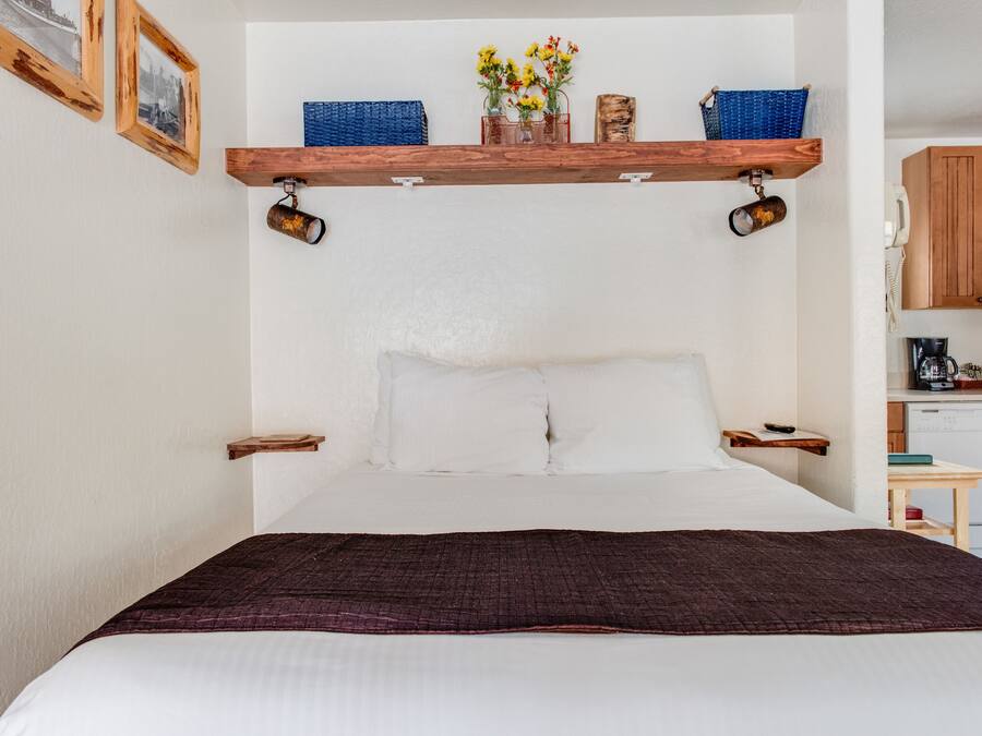 Un dormitorio con una cama grande, cabecera de madera y un estante sobre la cama con objetos decorativos.