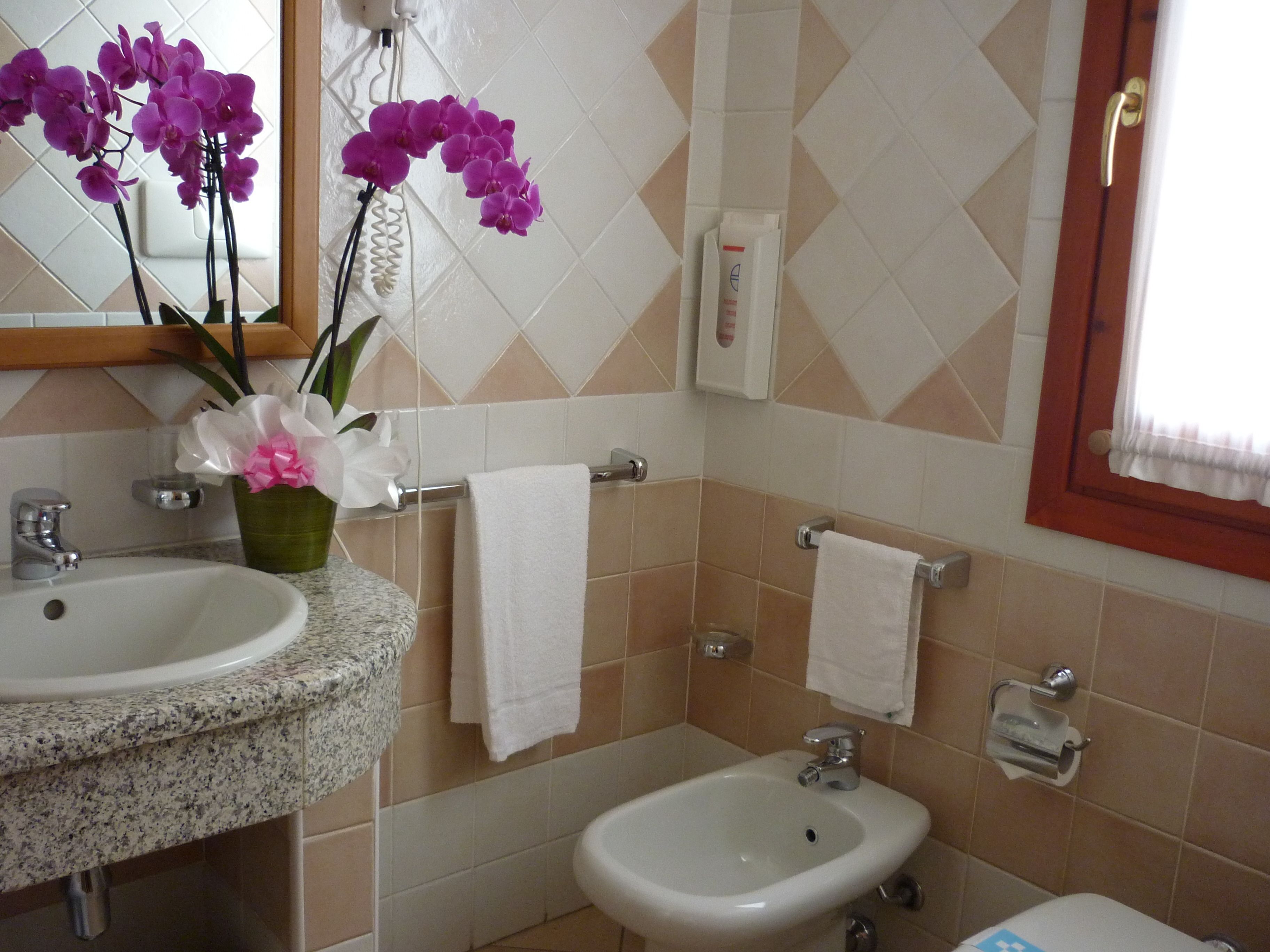 Une salle de bain avec un lavabo en granit, un petit lavabo blanc, deux serviettes et un miroir.