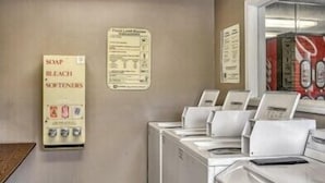 A laundromat with multiple washing machines and a wall-mounted sign listing soap, bleach, and softeners. - Siegel Select Gautier (Gautier)