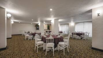 A conference room with multiple tables and chairs, carpeted floor, and ceiling lights.