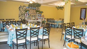 Un comedor con varias mesas dispuestas para el desayuno, con temática de jardín, adornado con plantas y un letrero que dice 'Welcome to Garden'.