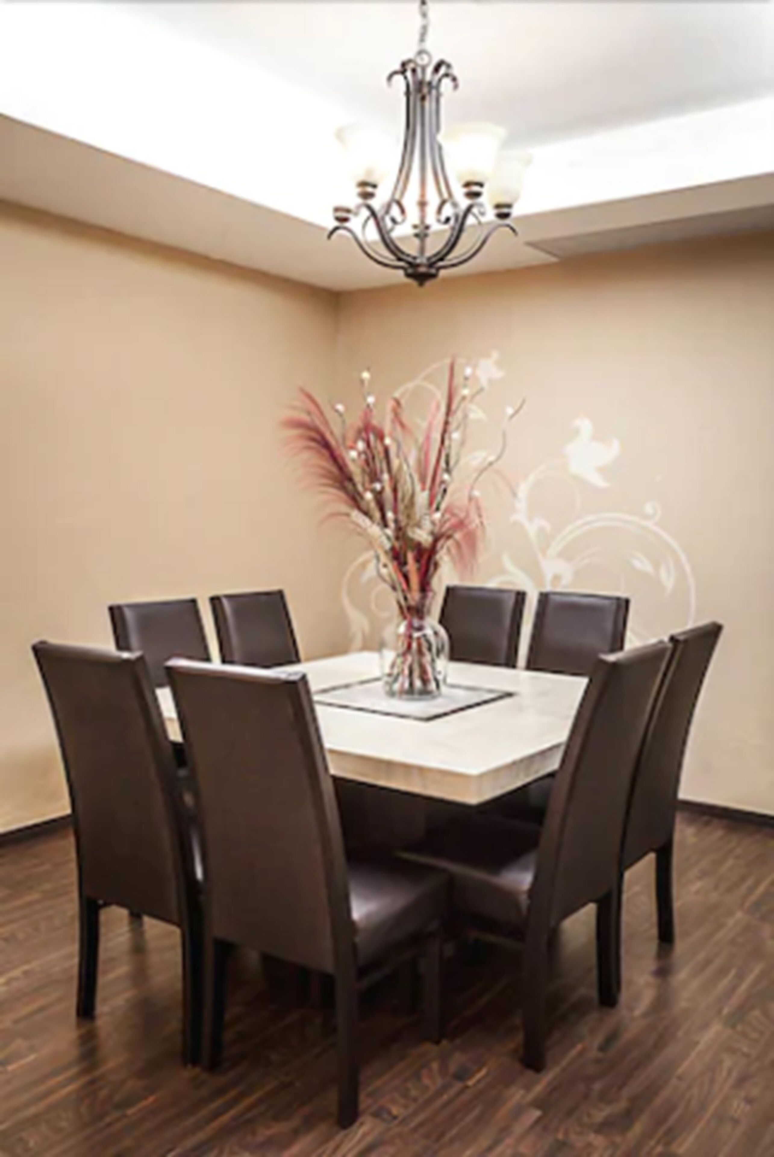 Comedor con una mesa redonda, seis sillas, una araña y un jarrón decorativo.