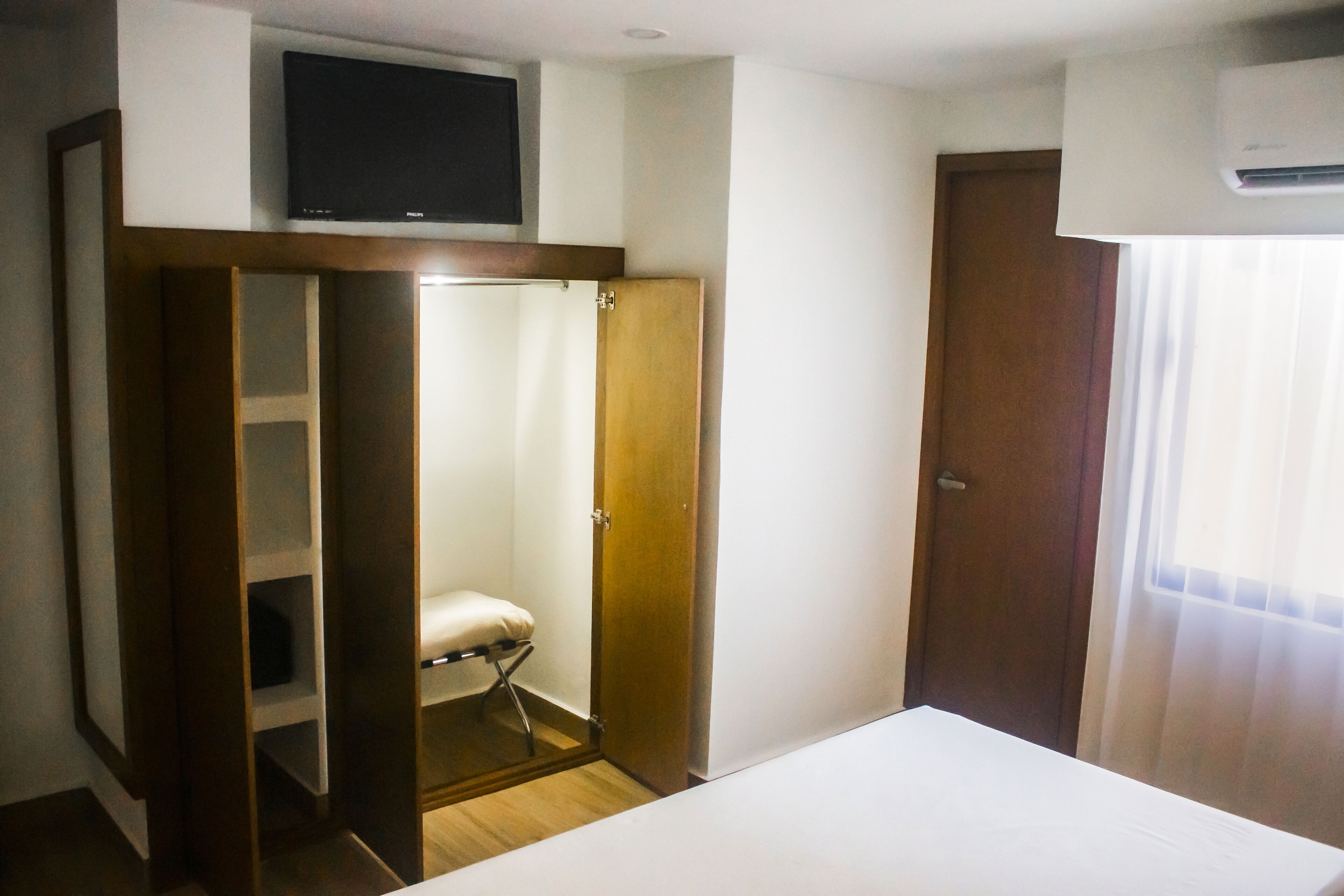 Une chambre à coucher comprenant un lit, une armoire, un téléviseur et un appareil de climatisation.