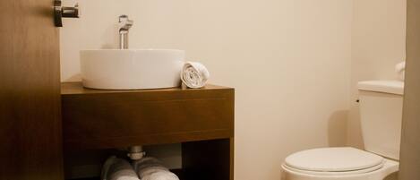 A bathroom with a white sink, a toilet, and a towel rack with towels.