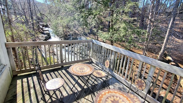 Una terraza de madera con vistas a un bosque y un arroyo.