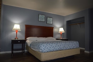 A bedroom with a wooden headboard, two bedside tables with lamps, a patterned bedspread, and two framed pictures on the wall.
