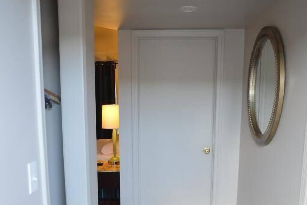 A hallway with a wooden floor, a white door, and a mirror on the wall.