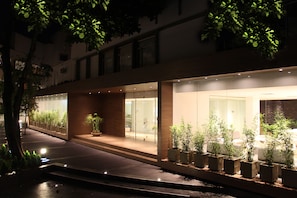 A modern building with a glass facade, outdoor seating area, and potted plants.