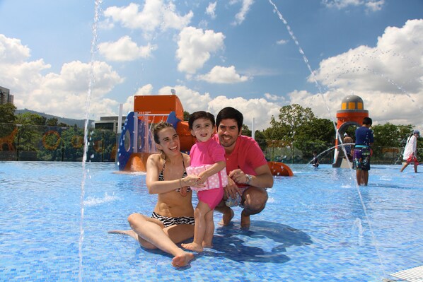 A family enjoying a water park with a pool, water slides, and various play structures.