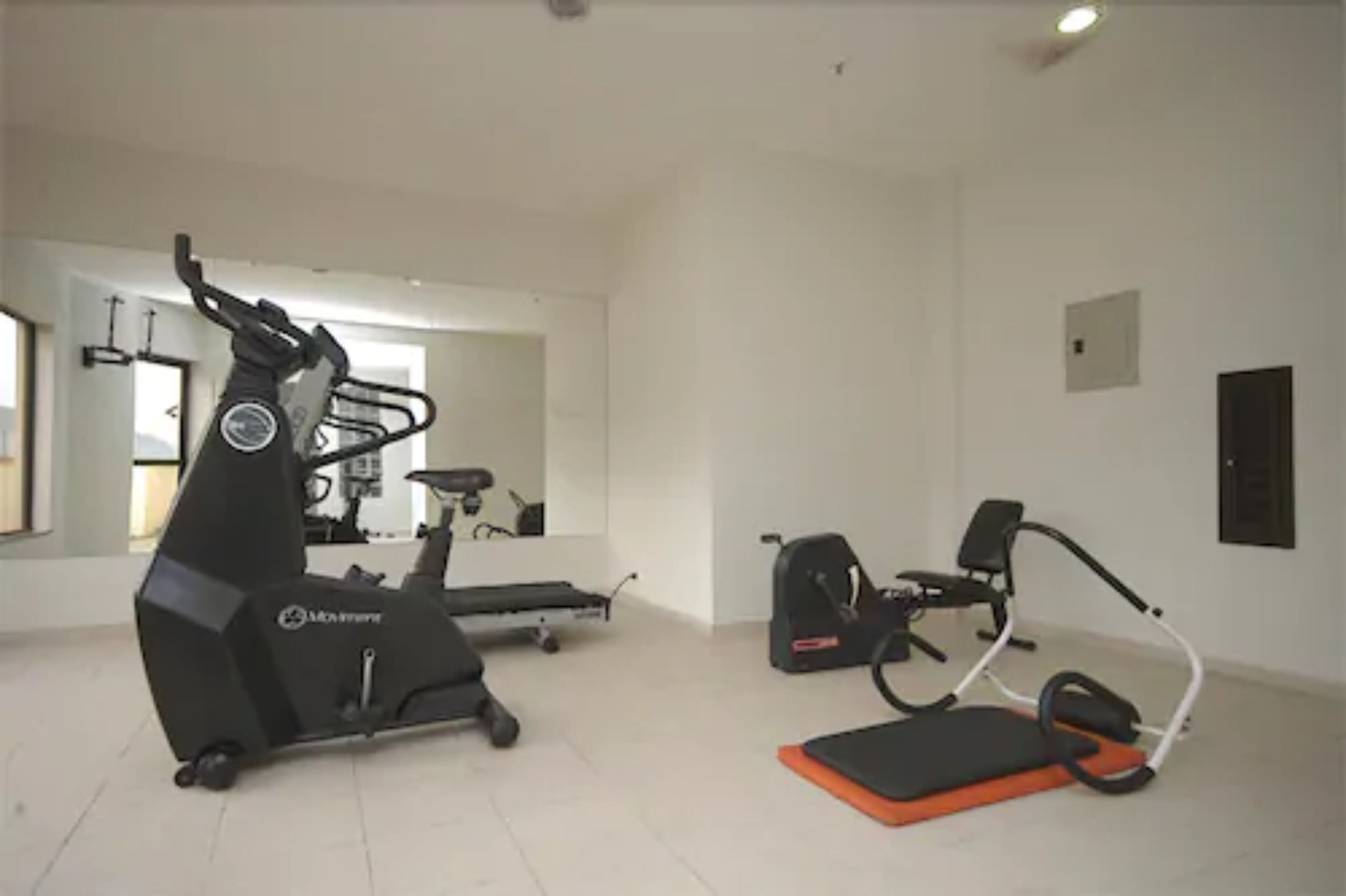 A home gym with an elliptical, a treadmill, and a stationary bike.