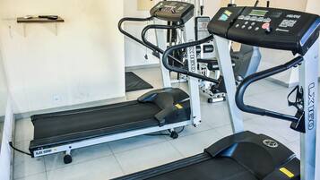 A gym with a treadmill, elliptical, and weight machines.