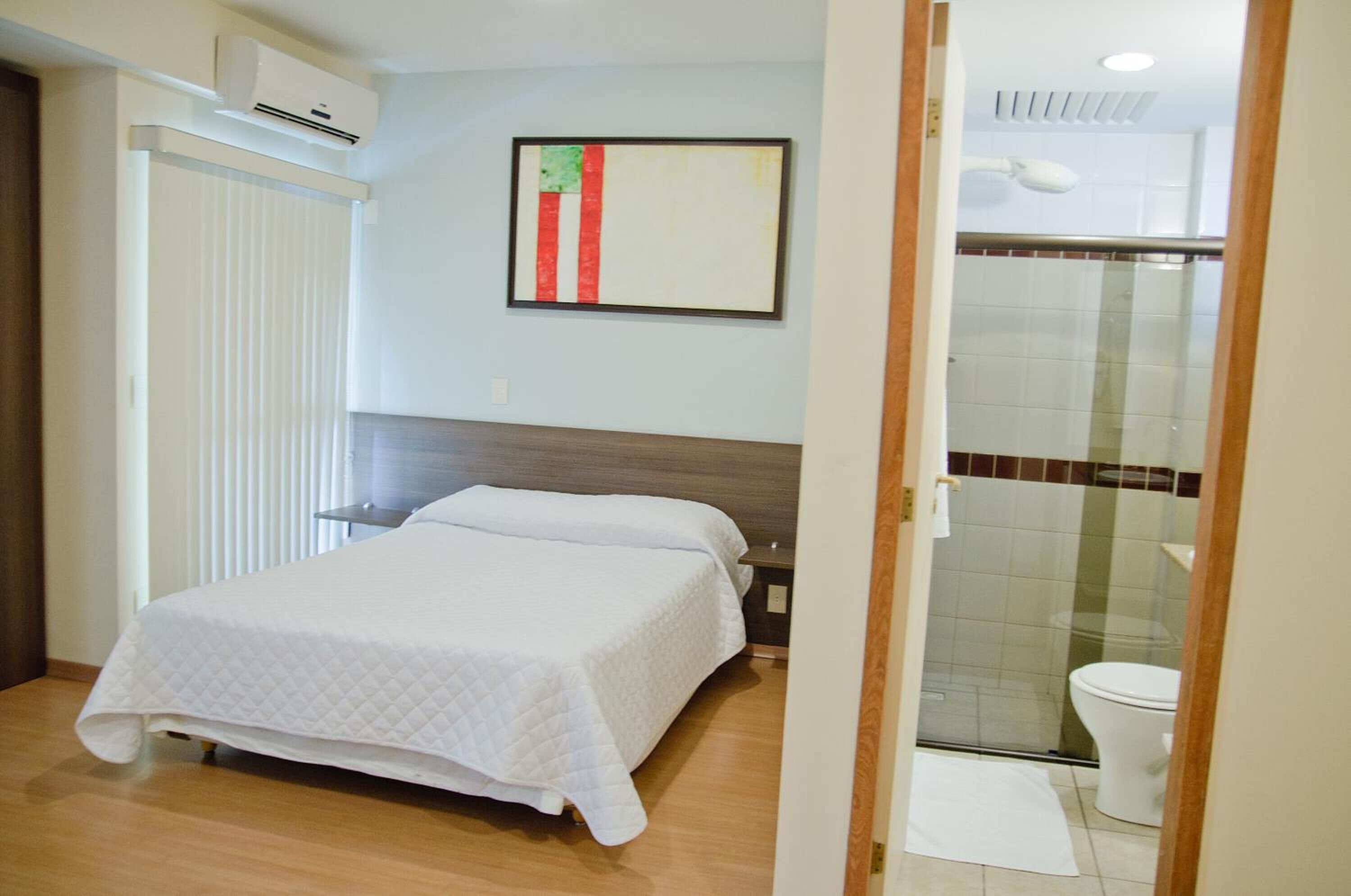 Una habitación de hotel con cama, ducha y baño con inodoro y lavamanos.