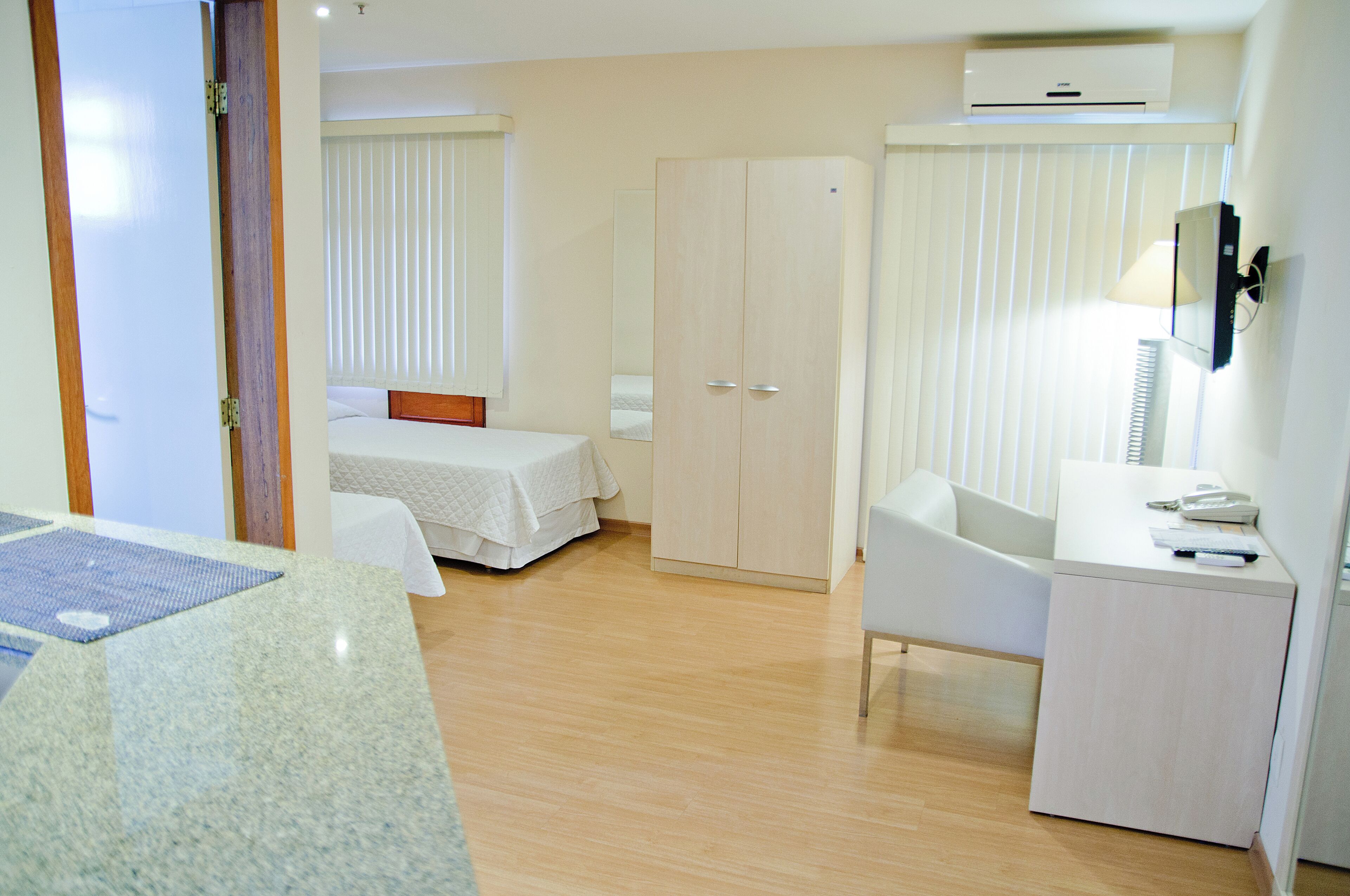 Une chambre d’hôtel avec deux lits, un bureau, une chaise, une armoire et une salle de bain.