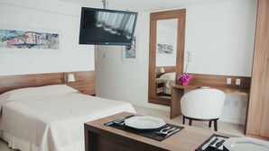 A hotel room with a bed, a desk with a mirror, a television, and artwork on the walls. - Mont Blanc Nova Iguaçu (Nova Iguaçu)