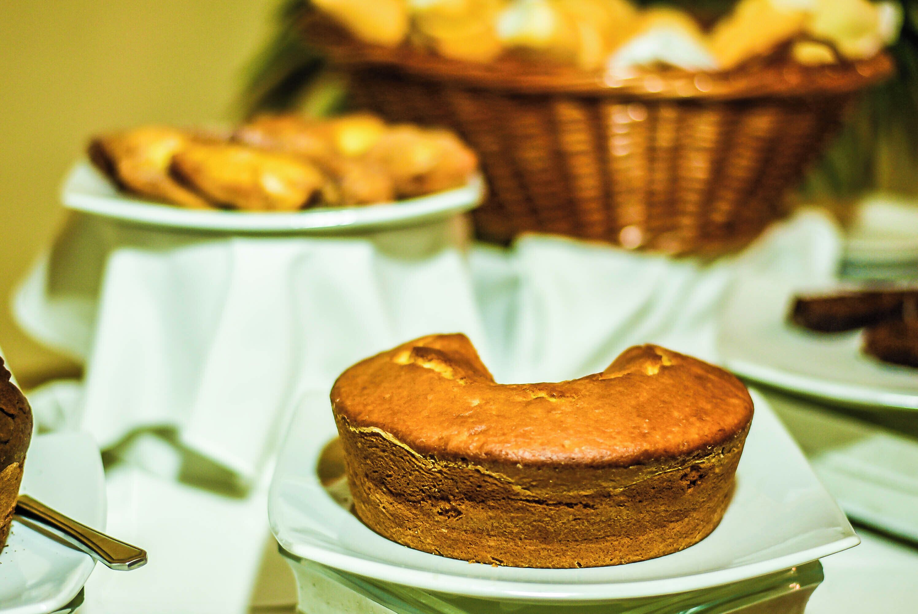Uma mesa com diversos produtos de panificação, incluindo muffins e doces, expostos em pratos brancos.