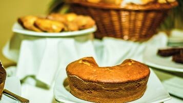 Uma mesa com diversos produtos de panificação, incluindo muffins e doces, expostos em pratos brancos.