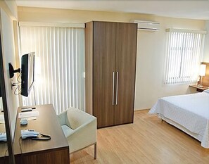 Habitación de hotel con cama, escritorio con teléfono, silla, armario y televisor.