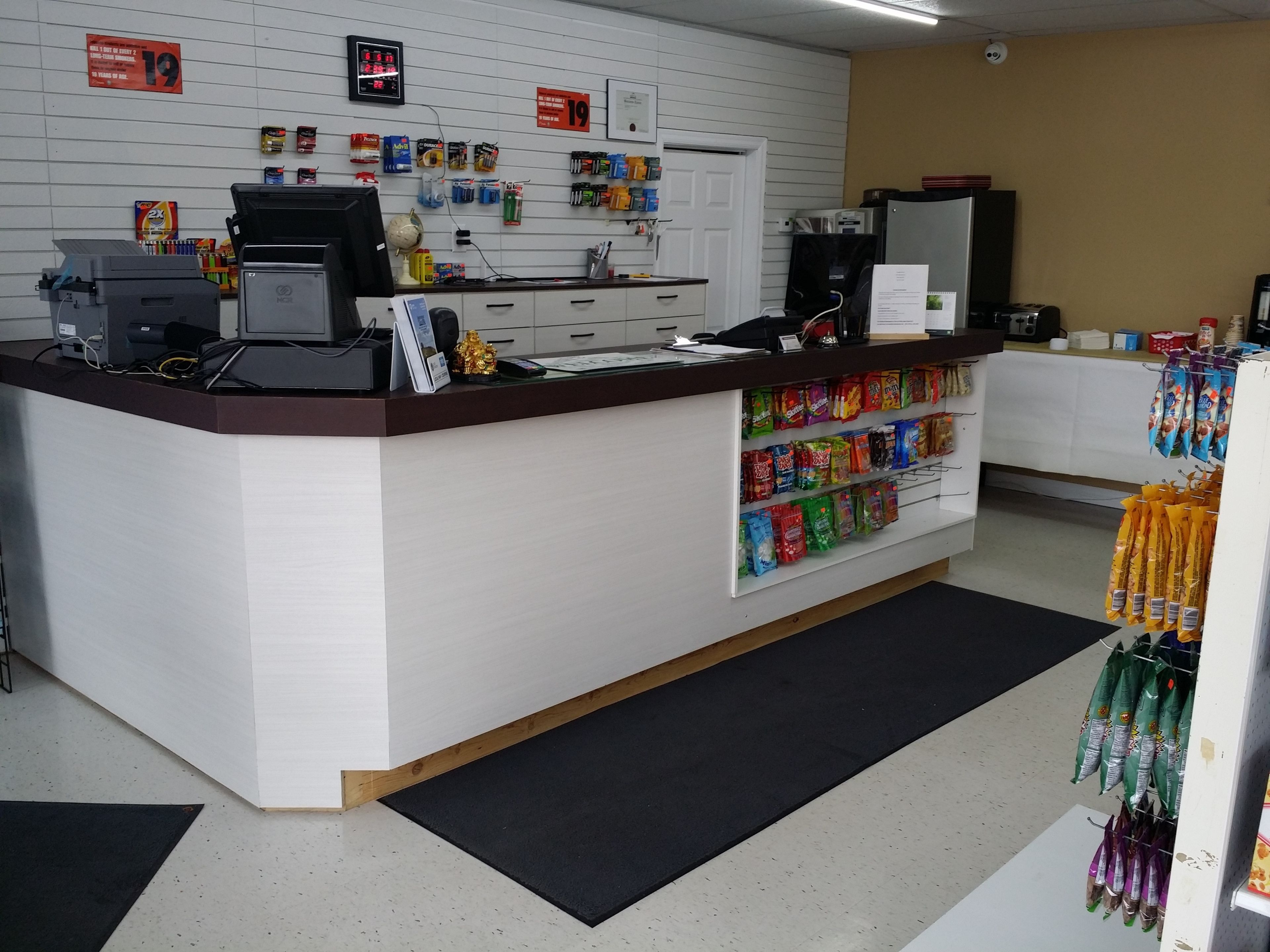 A reception area with a counter, a computer, a printer, and a wall-mounted clock.