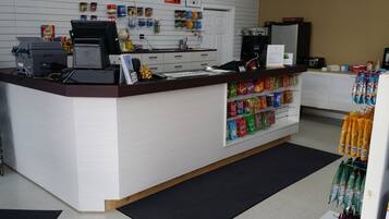 A reception area with a counter, a computer, a printer, and a wall-mounted clock.