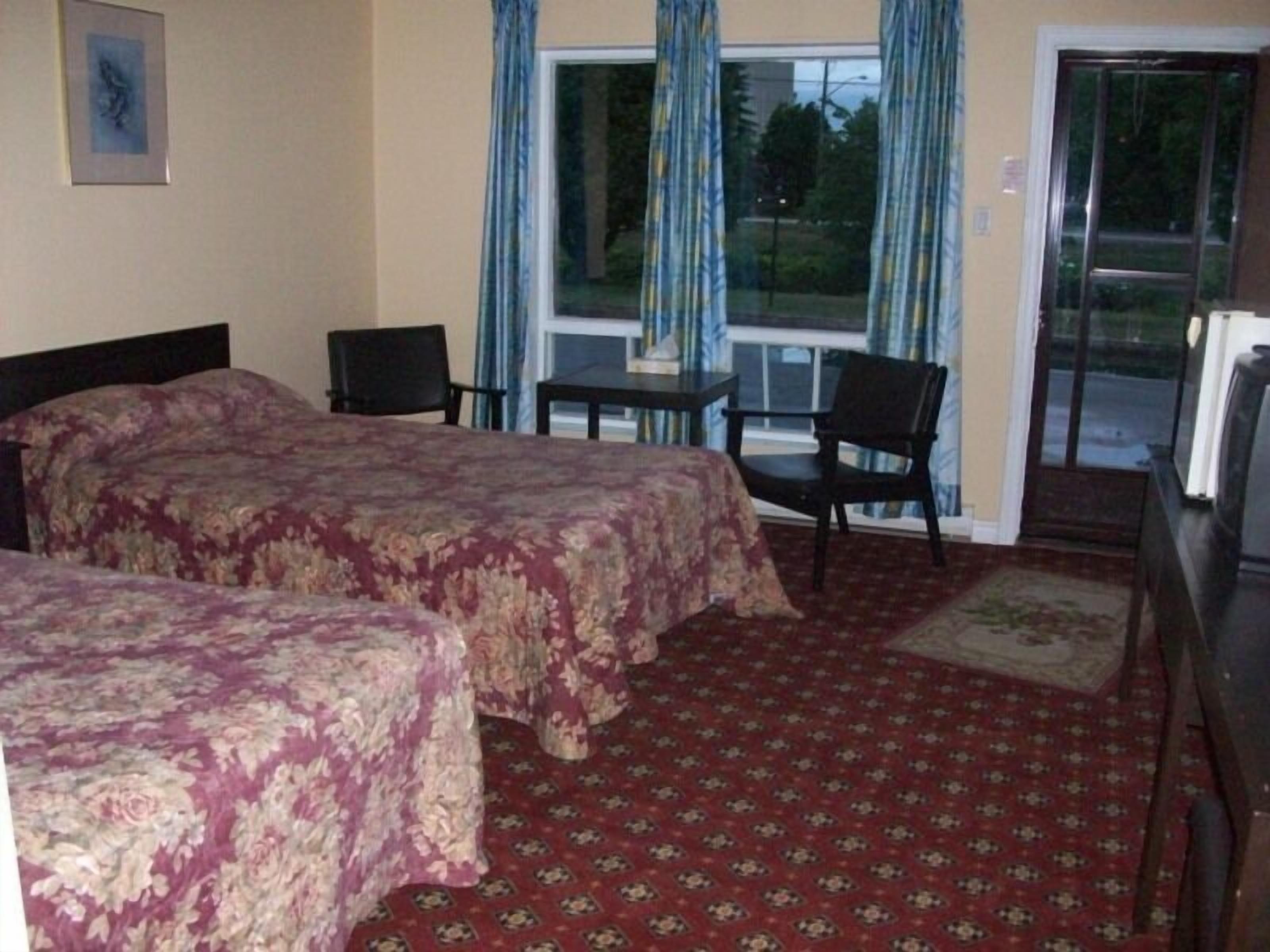 Une chambre d’hôtel avec deux lits, une petite table, une chaise et un téléviseur.
