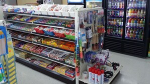 Una tienda de conveniencia con estantes llenos de aperitivos, bebidas y artículos para el hogar.