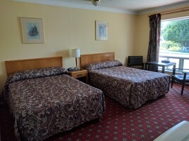 Habitación de hotel con dos camas, un escritorio, una silla y dos cuadros en la pared.