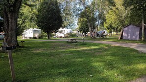 Un camping con vehículos recreativos, mesas de picnic y un cobertizo.