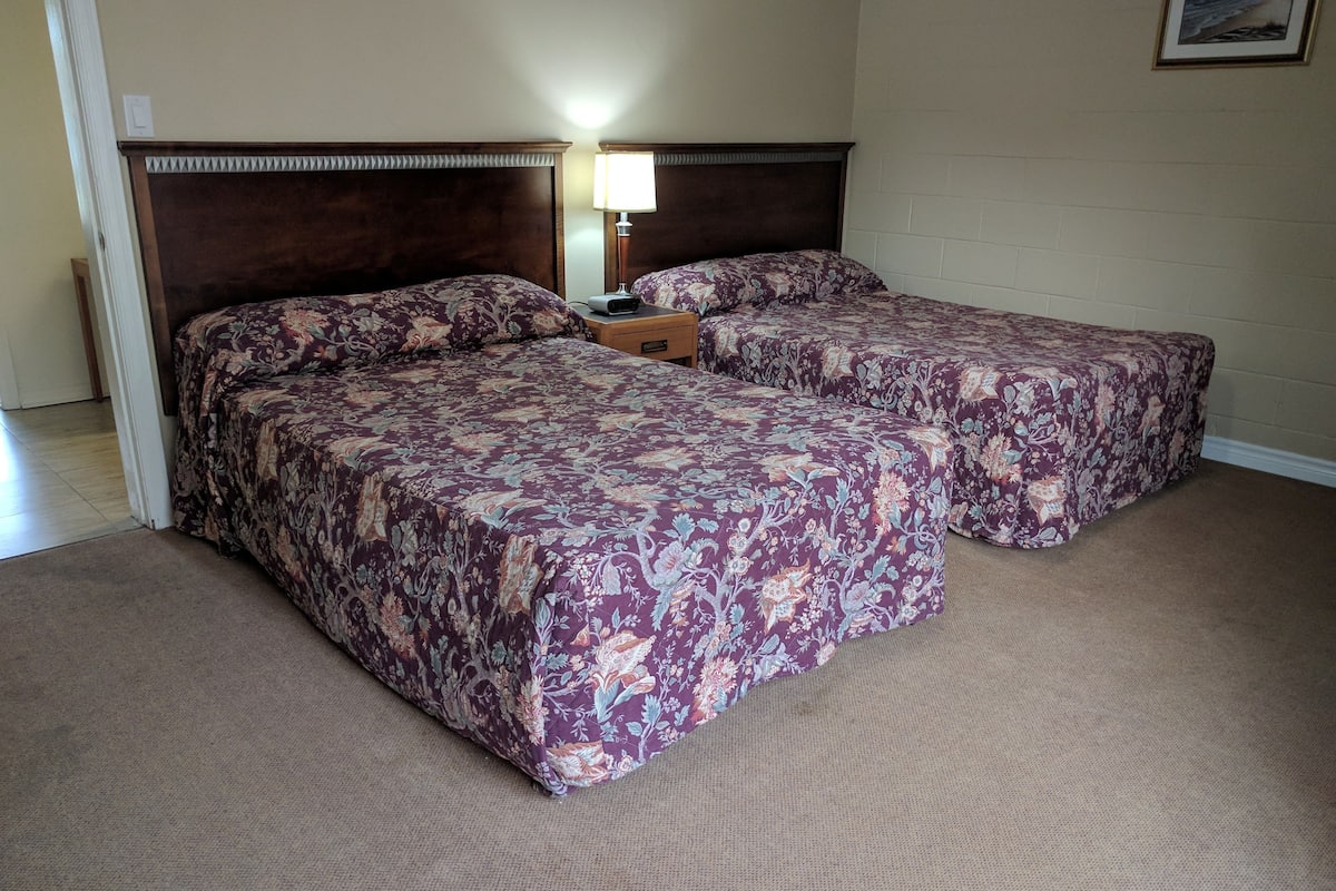 A double bed with a floral bedspread and two bedside tables with lamps.
