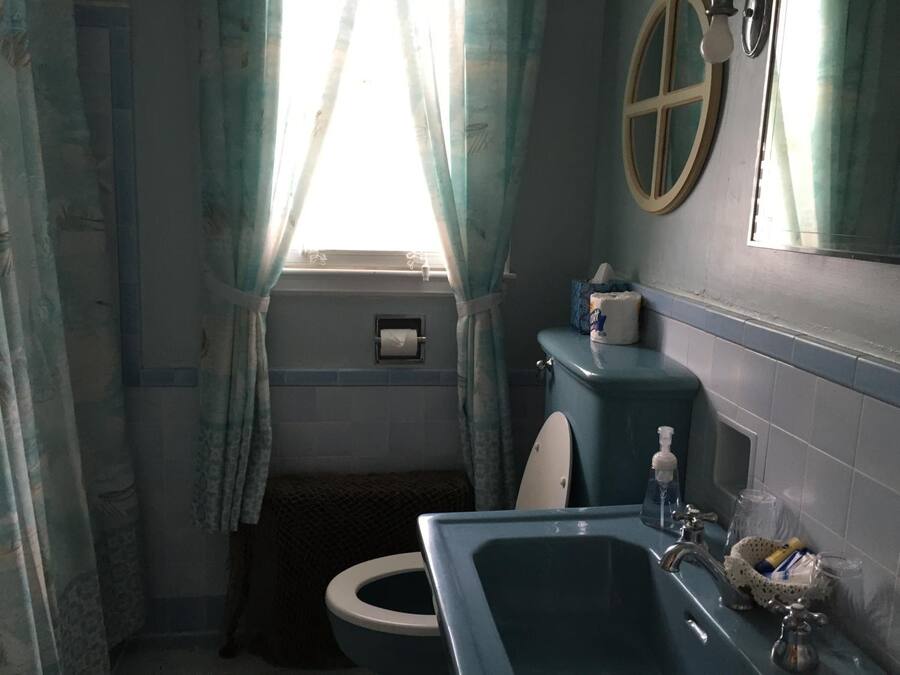 A bathroom with a toilet, sink, and a window with curtains.