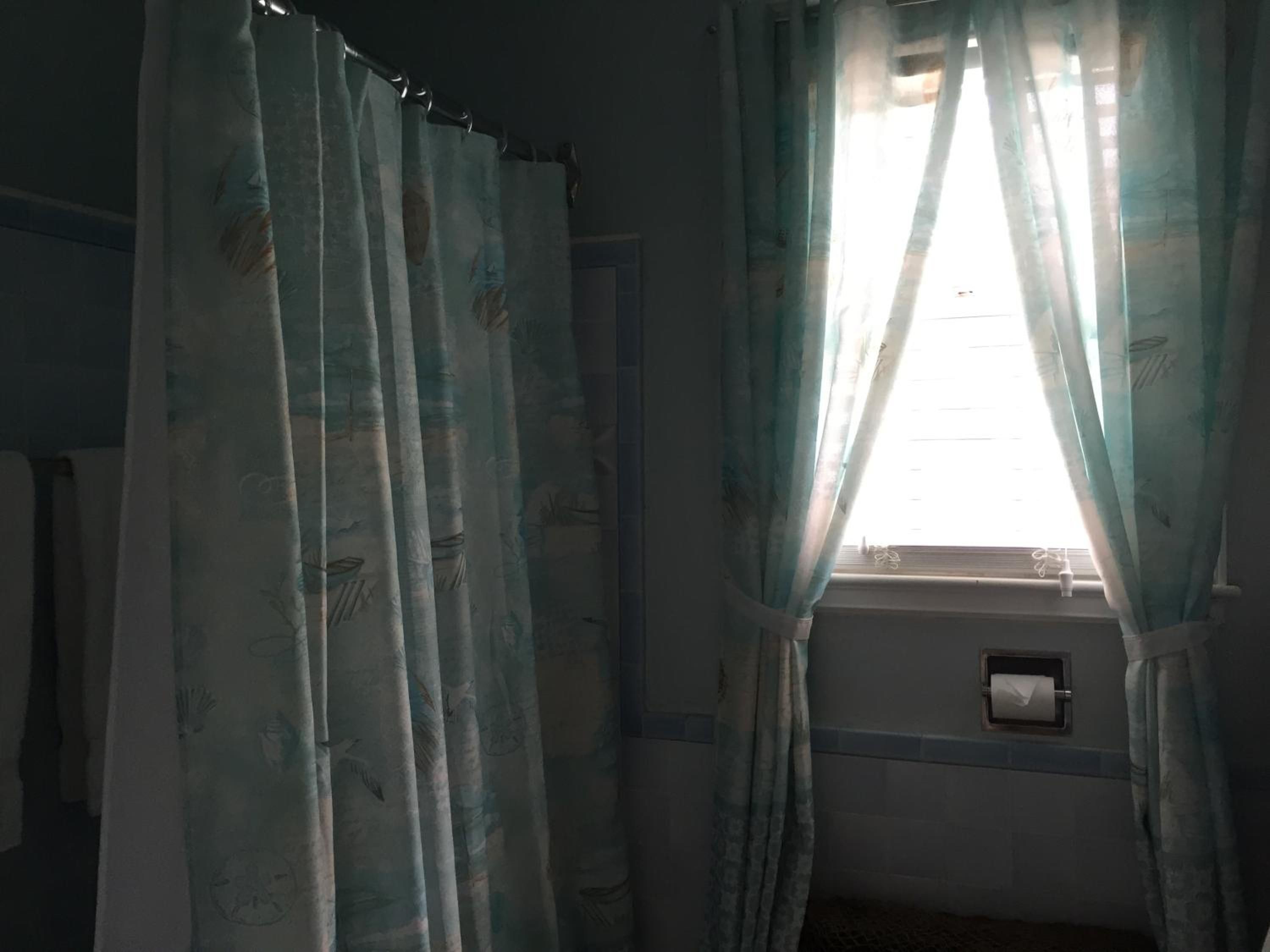 Una habitación con ventana, cortinas e aire acondicionado de pared.