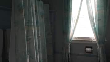 Una habitación con ventana, cortinas e aire acondicionado de pared.
