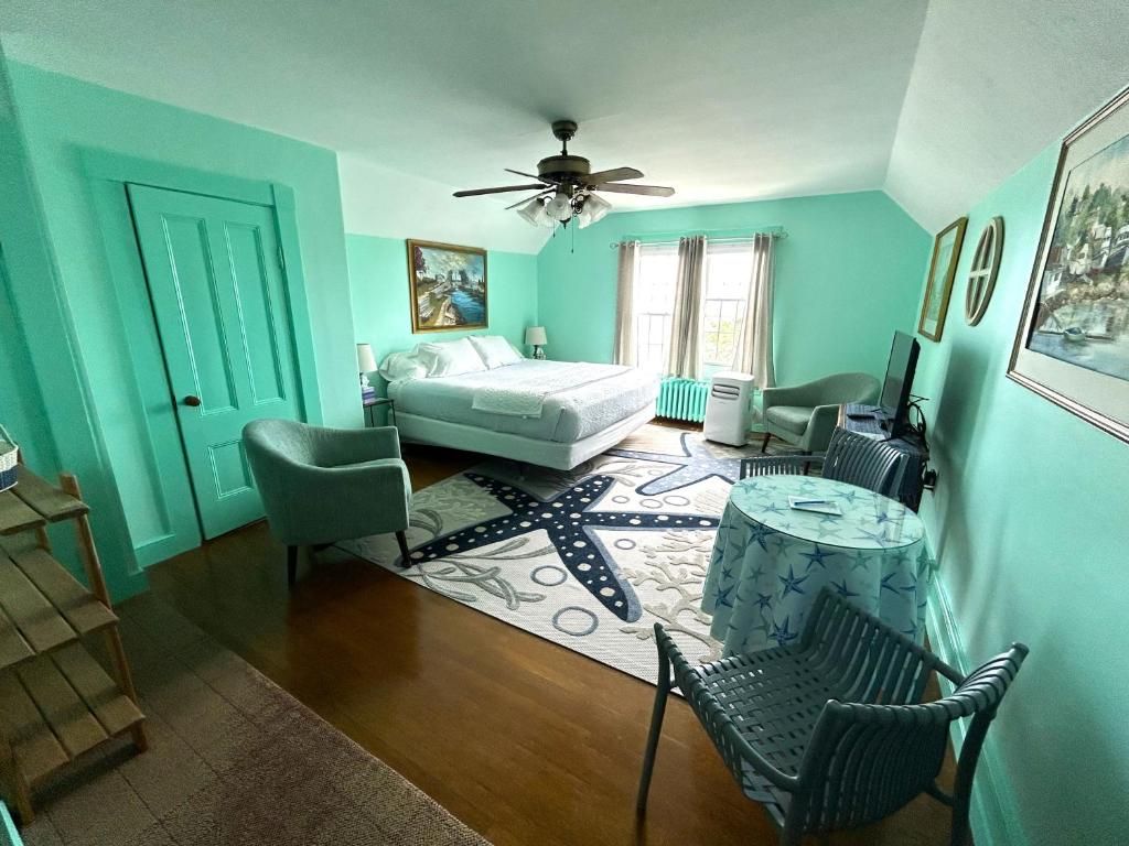 Una habitación con cama, escritorio, silla, ventilador de techo y ventana con cortinas.