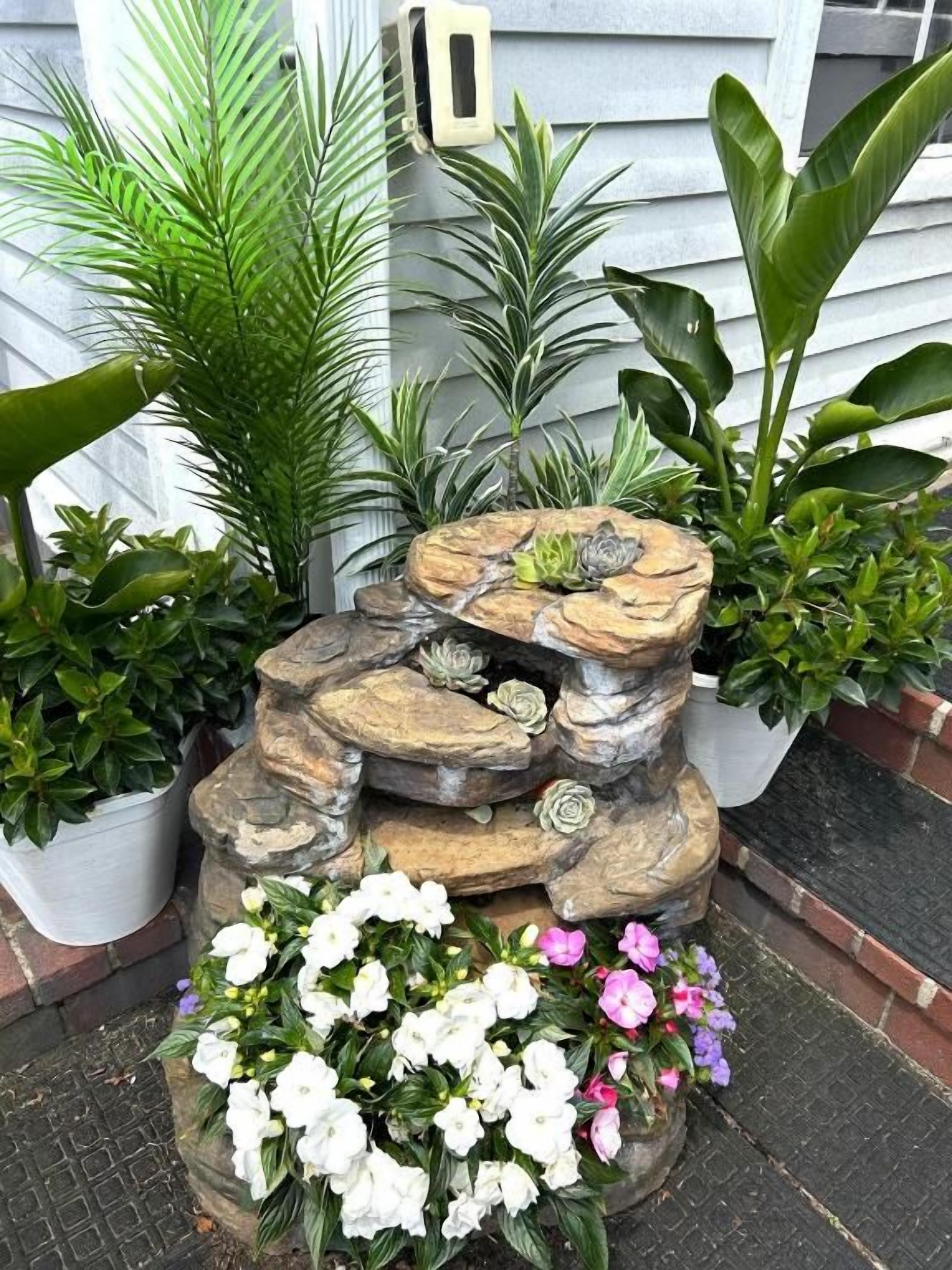 A tiered rock garden with various plants and flowers.
